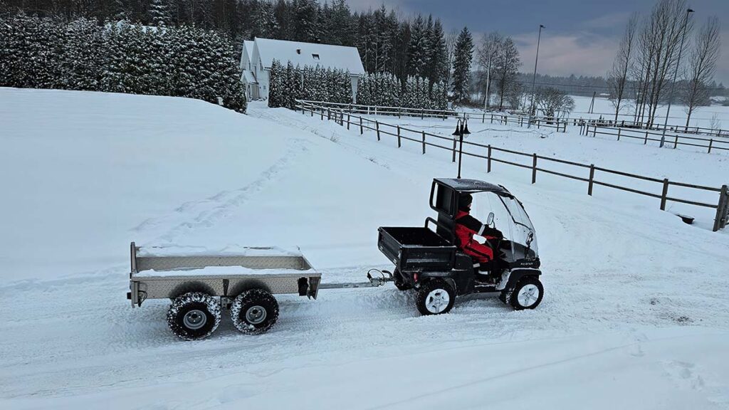 A Paxster Utility braves the winter, towing an ATV trailer to assist with farm work in a local agricultural setting